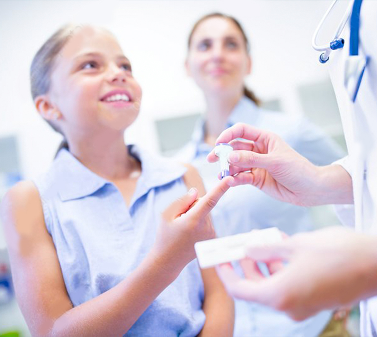 Child receiving a finger-prick blood sample for a C-Reactive Protein (CRP) test at Medical Center Playa del Inglés in Gran Canaria.
