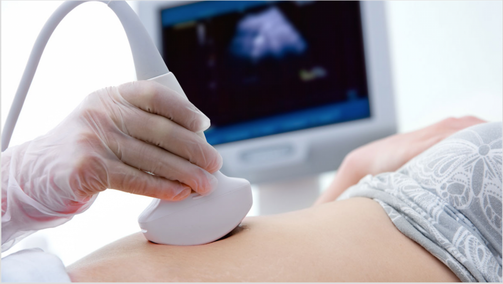Gloved healthcare professional performing an abdominal diagnostic ultrasound, with the ultrasound image visible on the monitor at Medical Center Playa del Inglés, Gran Canaria.